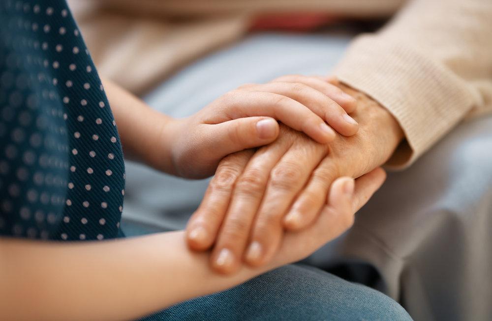Syracuse grandparent rights attorney gently holds an elderly person's hand, signifying care and warmth